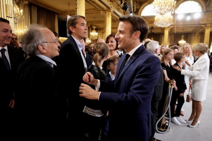 Brigitte Macron, derrière son époux, embrassant ses petits-enfants en 2022