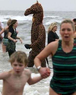 Un homme-girafe se promène à la plage