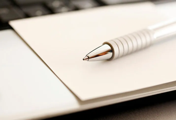 stylo en métal sur ordinateur portable avec du papier, image sépia