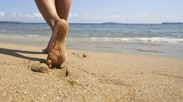 jeune femme marchant seul sur la plage de sable closeup détail de pieds féminins et de sable doré