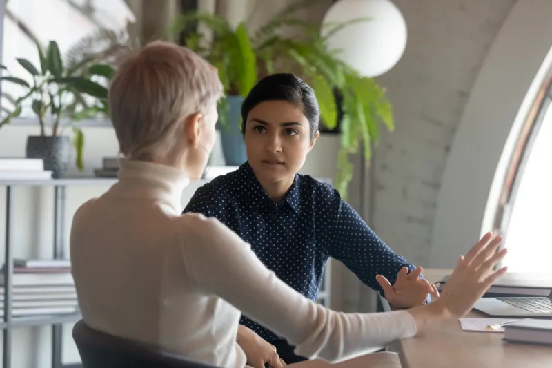 indian and caucasian businesswomen negotiating sit at desk in office lawyer consulting client during formal meeting job interview and hiring process diverse colleagues discussing project concept