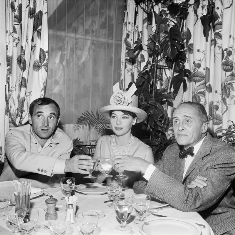 franco-american actress leslie caron toasts with french singer charles aznavour (left) and french stage director rené clair (right) in a restaurant on the champs-elysées, in july 7, 1962 (photo by -   afp)