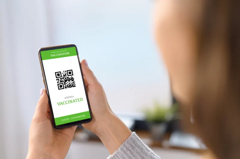 the smartphone screen with an international covid passport in hand of a woman, coronavirus vaccination confirmation, display of mobile phone with an approved necessary vaccine certificate for travel