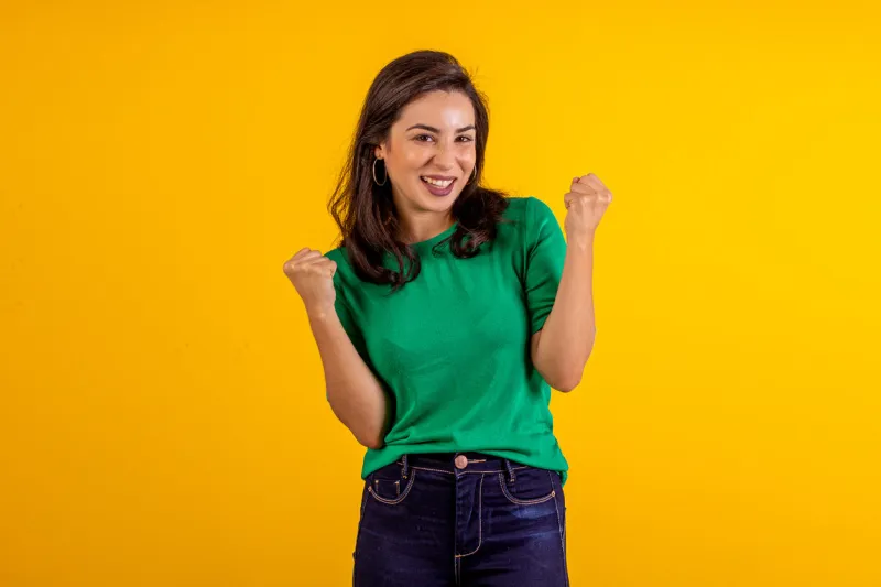 studio shot of young woman in blue shirt on yellow background with various facial expressions
