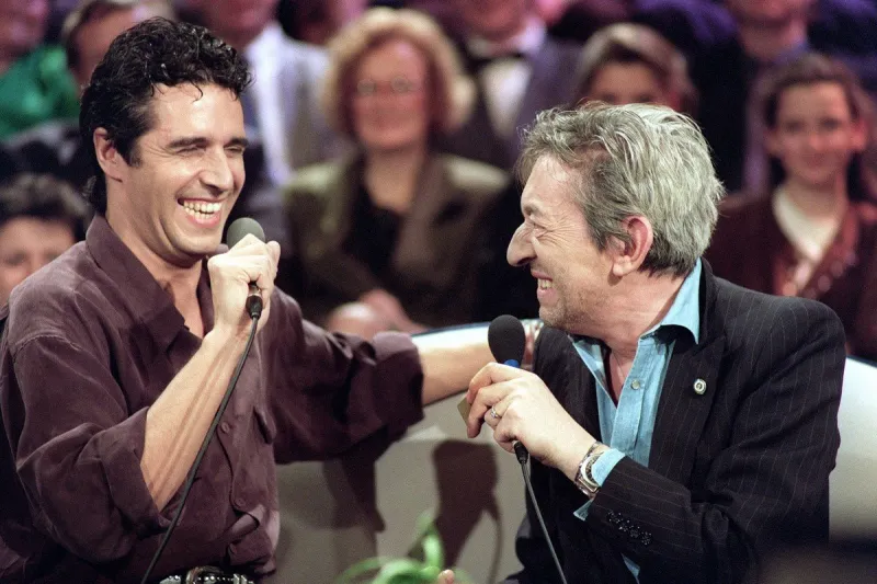 les chanteurs français serge gainsbourg et julien clerc plaisantent sur le plateau de l'émission de tf1 sacré soirée, le 14 mars 1990 à paris (photo by patrick kovarik   afp)