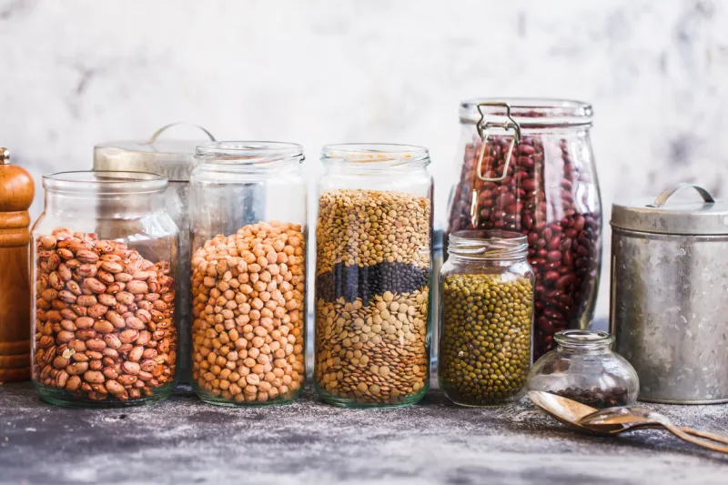collection of grain products, lentils, peas, soybeans and red beans in storage jars over on kitchen rural table vegetarian products