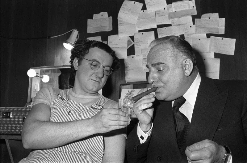 french humorist coluche (l) lights a cigare to bruno coquatrix (r), founder of the paris olympia concert hall, on february 19, 1975 after his performance at the olympia in paris afp photo (photo by afp)