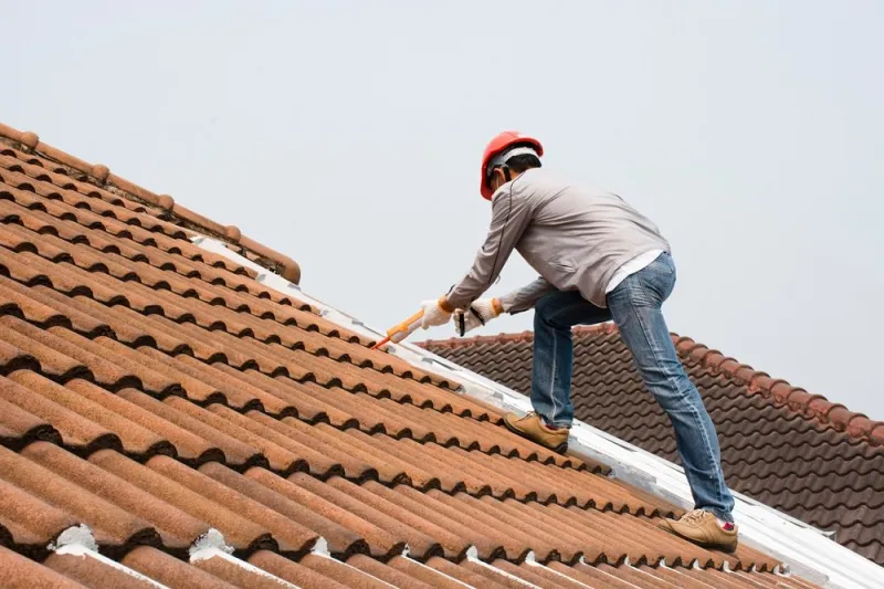 technician man hand using glue gun with silicone adhesive or manual caulking gun with polyurethane to seal the leakage on the roof installing and building construction concept