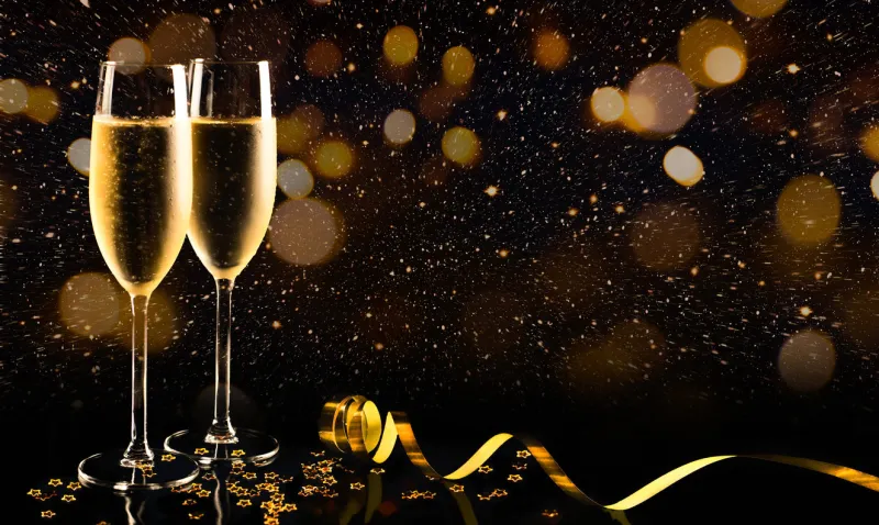 two glasses of champagne with golden confetti, glitter, serpentine and lights night of celebration concept