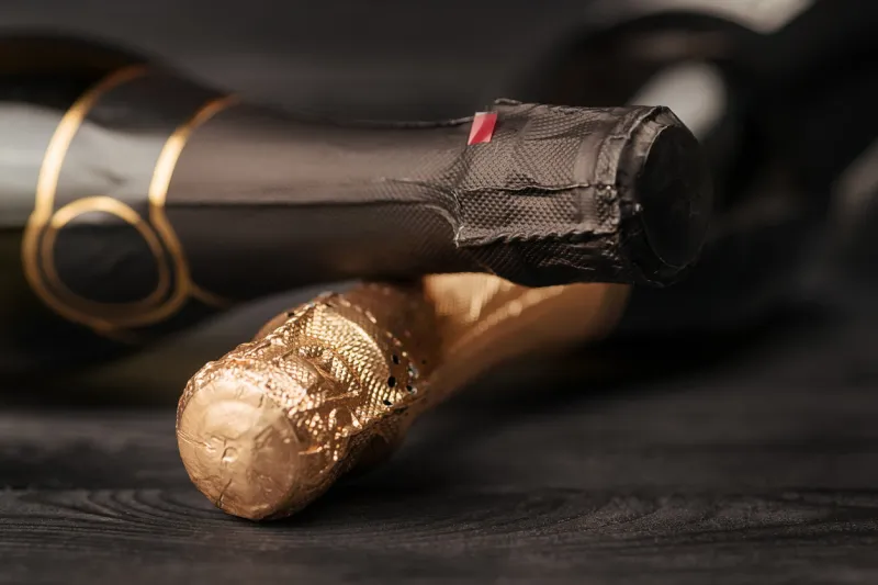 two champagne bottles on black wooden table selective focus