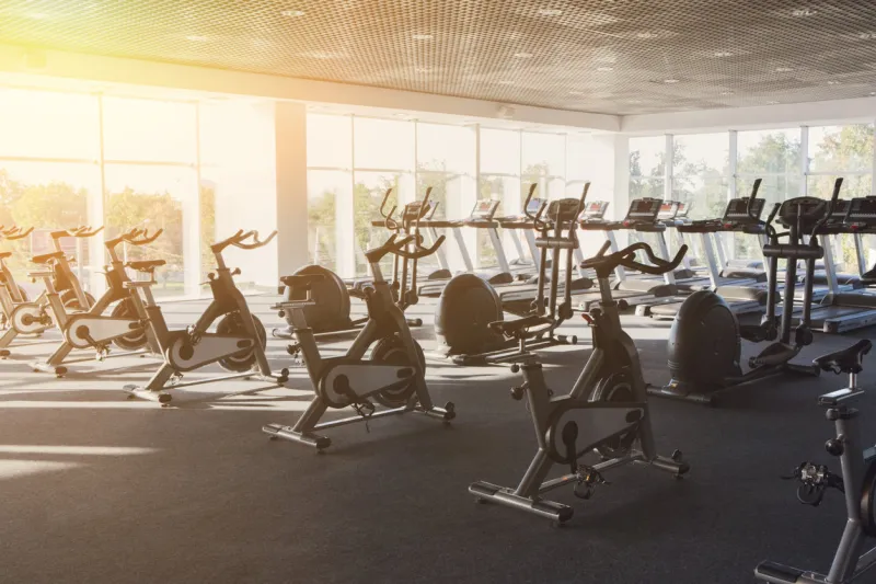 modern gym interior with equipment fitness club with row of training exercise bikes, backlight healthy lifestyle concept filtered