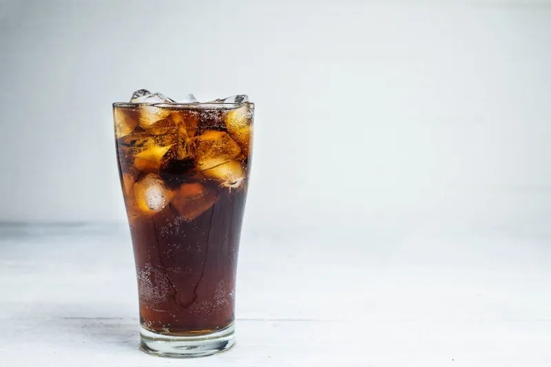 cola soda in a glass on a white table isolated