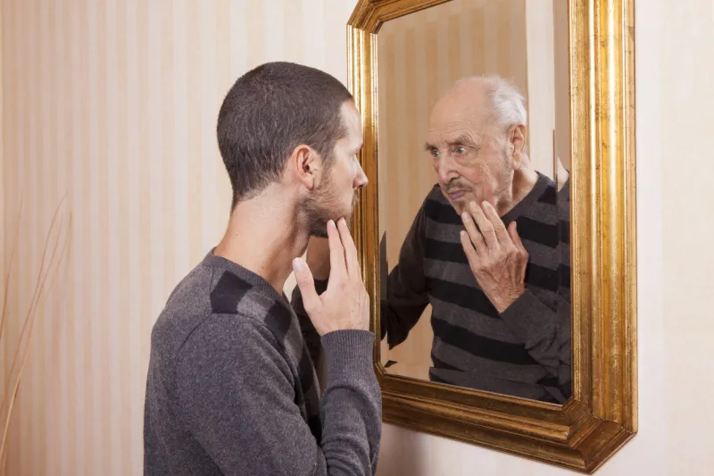 young man looking at an older himself in the mirror