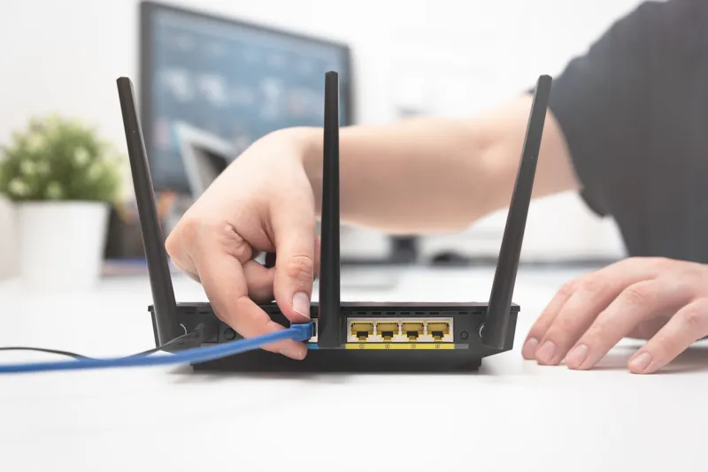 man connects the internet cable to the router's socket fast and wireless internet concept