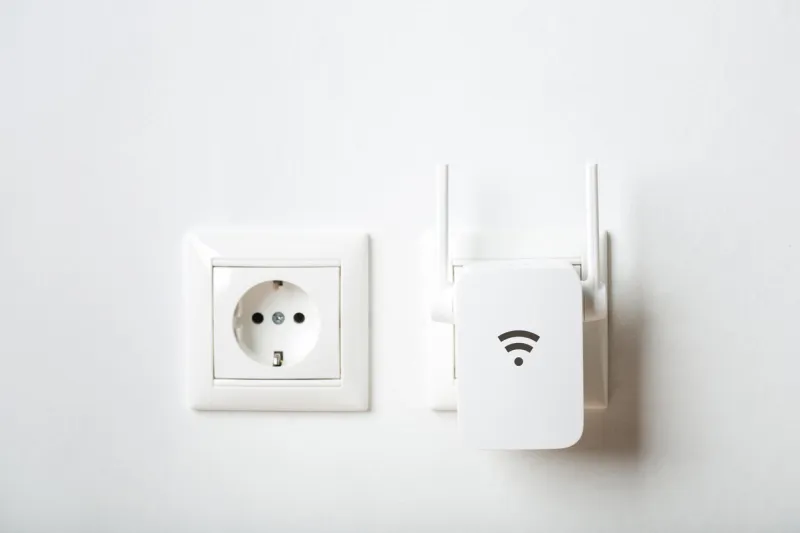 white wi-fi repeater indoors at home in outlet wireless router