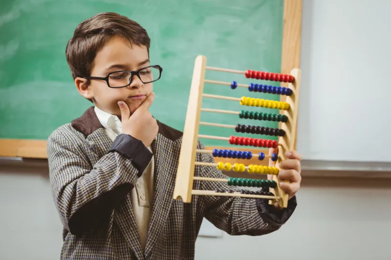 pupil dressed up as teacher holding abacus in a classroom