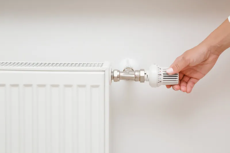 woman hand adjusting temperature of radiator closeup