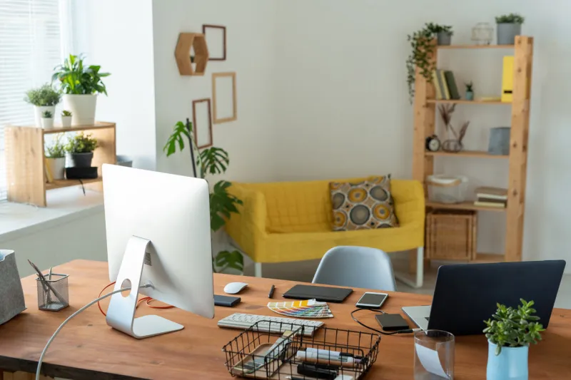 workplace of contemporary manager or freelancer with computer monitor standing on wooden table surrounded by home environment