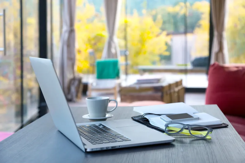 cozy workplace of freelance occupation person with portable computer coffee notepad located on wooden table in suburban cottage terrace