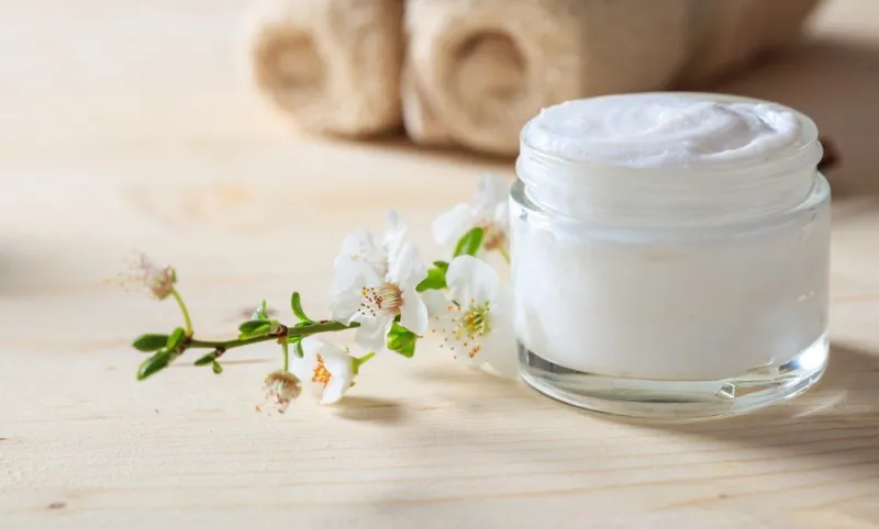 moisturizing cream and almond blossoms on wooden background
