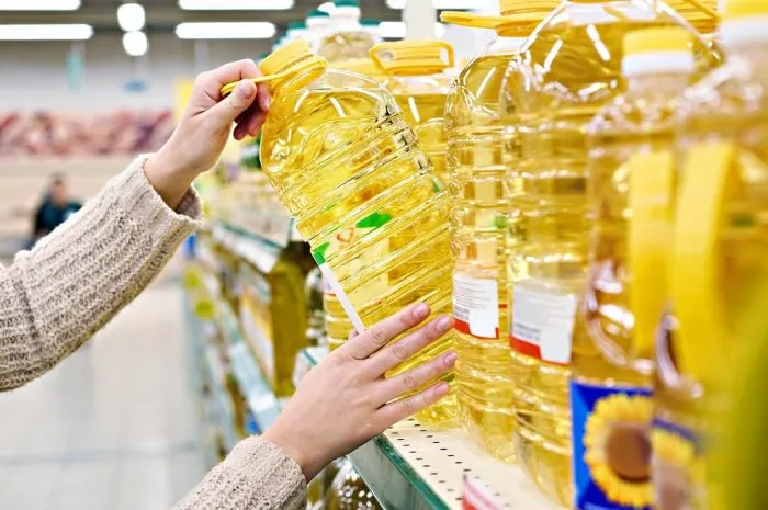buyer takes sunflower oil from the shelf in the store