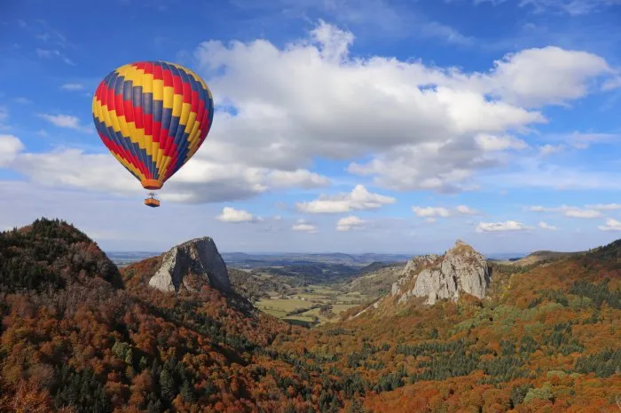 hot air balloon flying over ancient volcanos area tuiliere and sanadoire rocks monts dore, auvergne, france