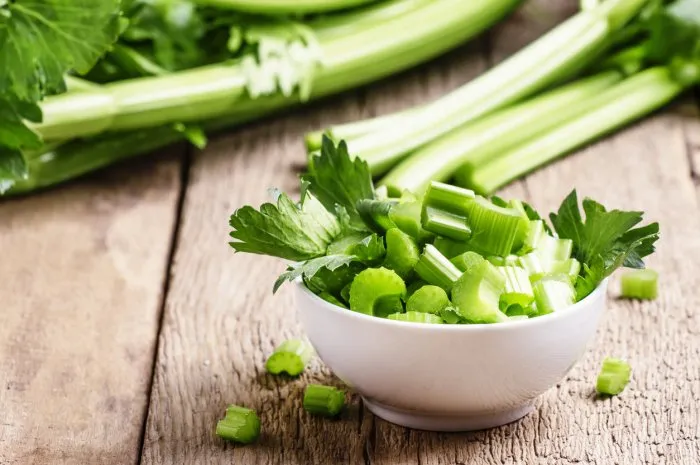 fresh sliced celery in a white bowl on a vintage wooden background, selective focus