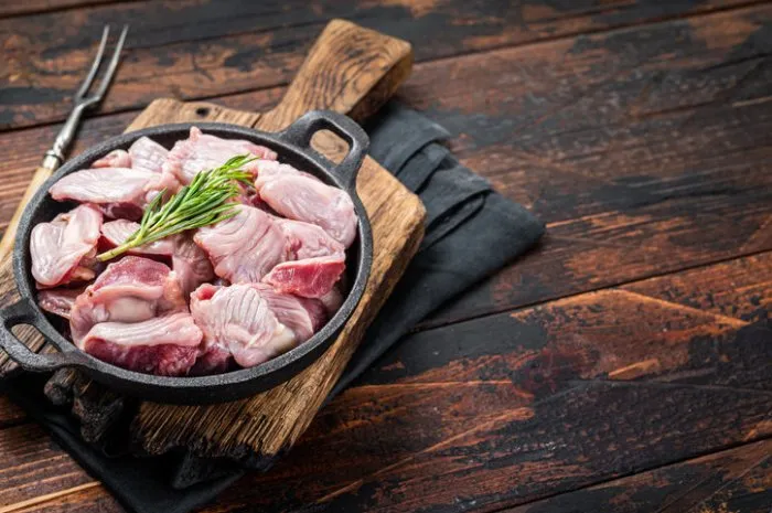 raw chicken giblets gizzards, stomachs in a skillet ready for cooking wooden background top view copy space