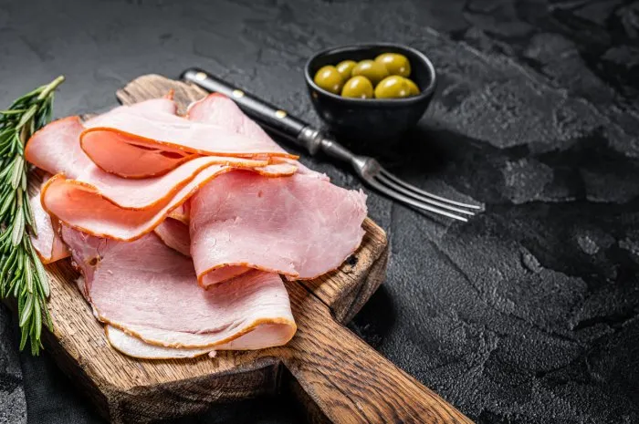 pork ham slices on cutting board, italian prosciutto cotto black background top view copy space