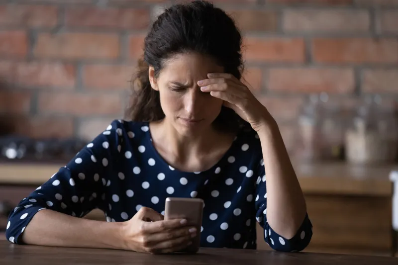 worried latin woman having problems with mobile phone, using wrong working apps, getting annoyed with spam, reading message with bad news, feeling stress, angry about cellphone breakdown