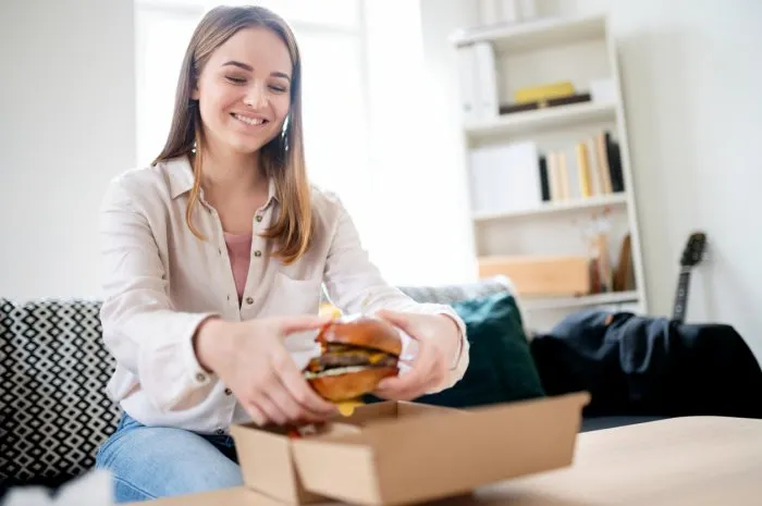 rear view of young woman with tablet ordering food at home, coronavirus and food delivery concept