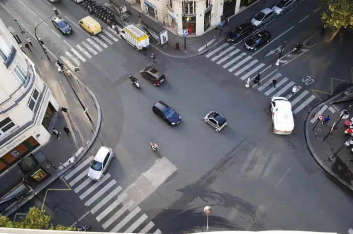 four road junction with cars in paris and people crossing the street