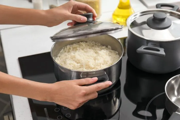 woman cooking rice on stove in kitchen