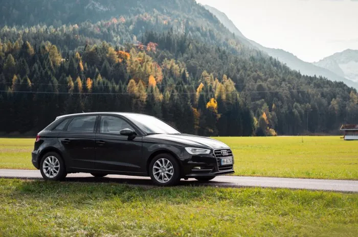 tirol, austria - october 23 2016  audi a3 in alpine valley with autumn forest in the background roadtrip through austrian countryside