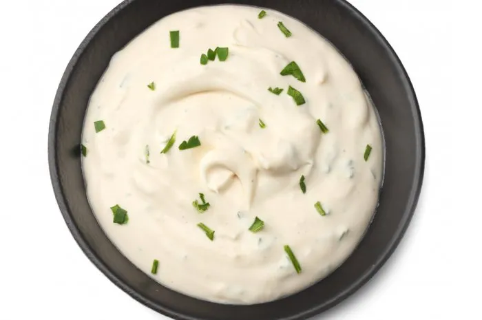 garlic sauce in black bowl isolated on white background top view