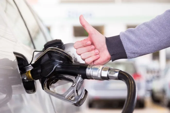 petrol or gasoline being pumped into a motor vehicle car closeup of man, showing thumb up gesture, pumping gasoline fuel in car at gas station