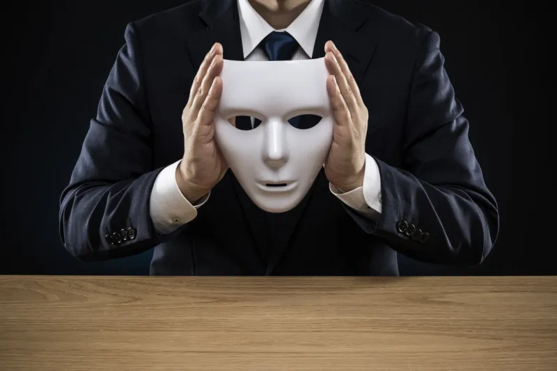 man in a suit removes his mask