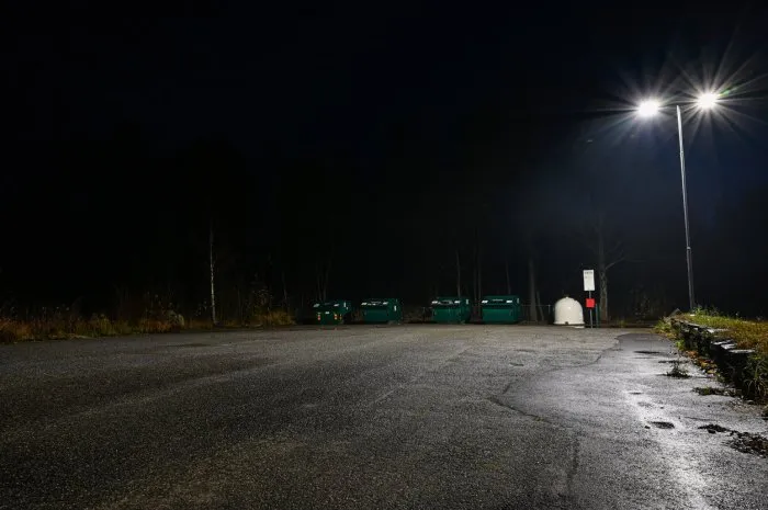 containers for recyceling covered in electric light a dark evening in hallabrottet sweden november
