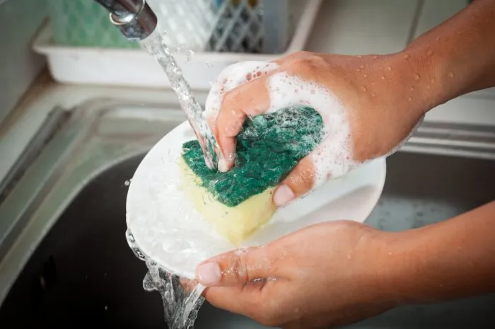 woman hand washing dishes over the sink in the kitchen