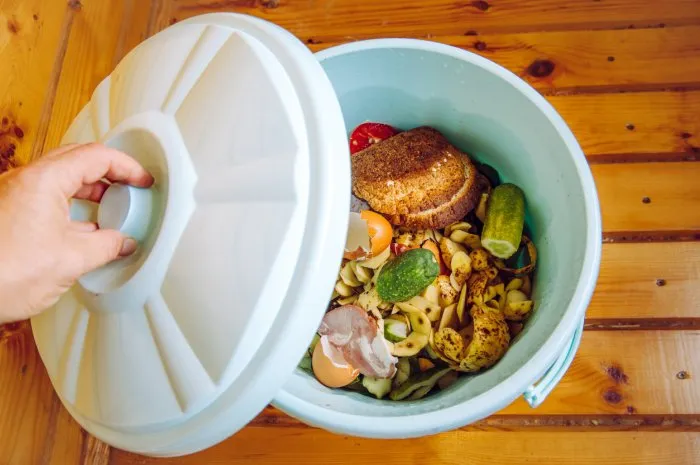 organic food waste in garbage bin bucket with lid in home on floor to be composted