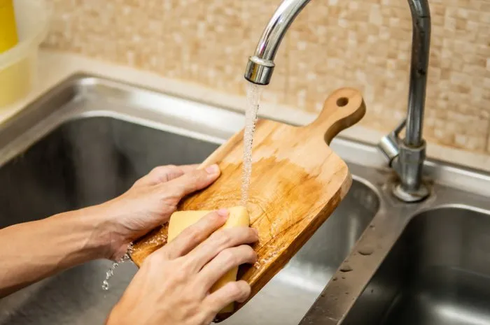 cleaning wood cutting board in kitchen sink