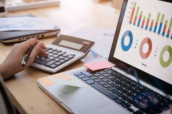 business woman uses a calculator to calculate the company's performance figures, graphs the monthly graphs for the meeting