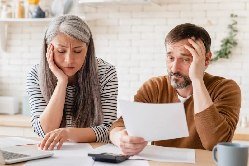 sad disappointed mature middle-aged couple family wife and husband counting funds, savings, declarations, investments,paperwork, financial documents, bankruptcy, court case, bills, pension at home