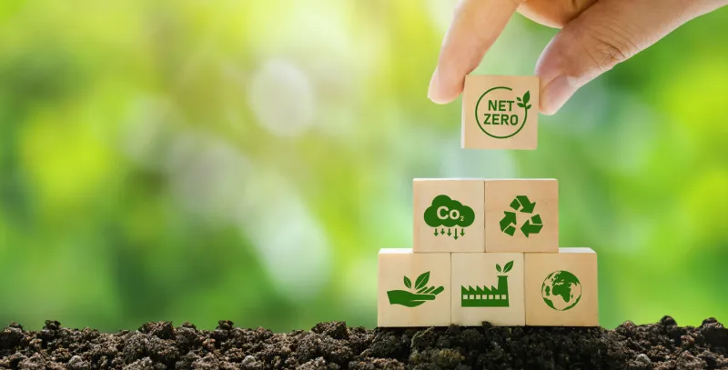 net zero and carbon neutral concepts net zero emissions goals a climate-neutral long-term strategy ready to put wooden blocks by hand with green net center icon and green icon on gray background