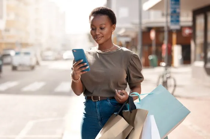shot of an attractive young woman using her cellphone outside while shopping in the city