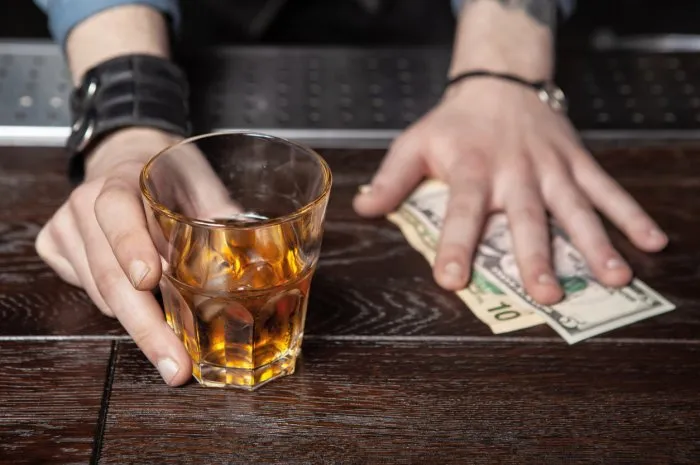 close up of a bartenders hands holding glass of whiskey and taking money