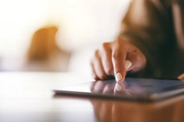 closeup image of a woman pointing finger at tablet pc on wooden table