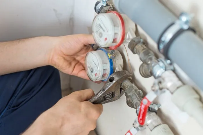 male plumber fixing water meter with adjustable wrench