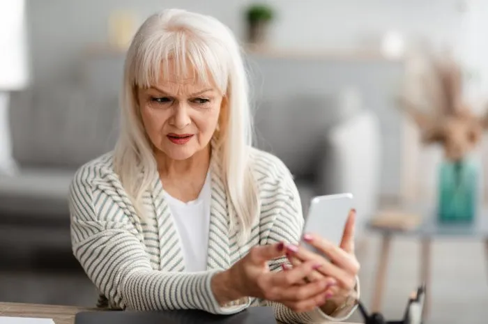 suspicious sms worried mature woman looking at smartphone screen, received bad news, got fishy scam message, doubtful confused lady holding gadget with concerned face expression, free copy space