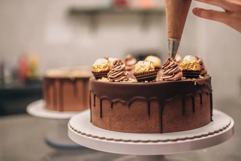 confectioner decorating chocolate cake, close-up
